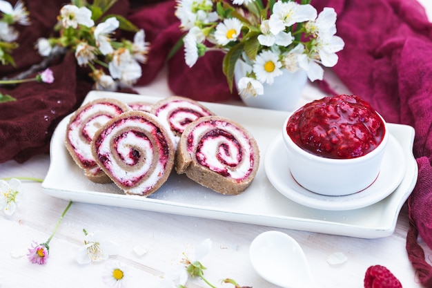 Amazing view of tasty looking raspberry rolls and raspberry jam put on a white plate