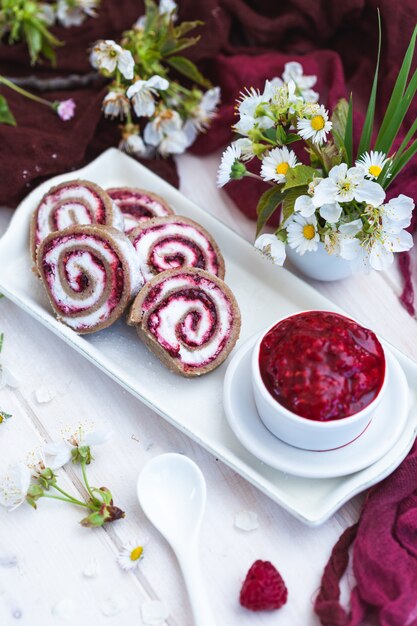 Amazing view of tasty looking raspberry rolls and raspberry jam put on a white plate