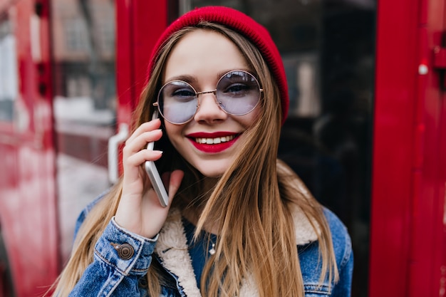 Amazing white woman in denim jacket posing with phone on red