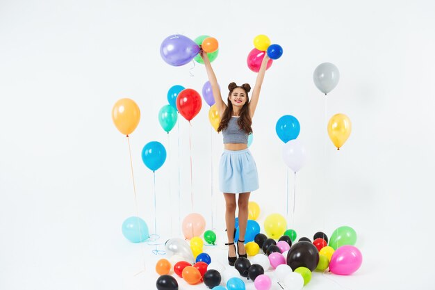 Amazing woman looking straight, holding helium ballons on white