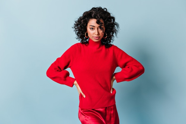 Amazing woman in red sweater standing with hands on hips