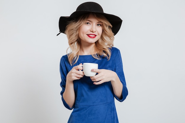 Amazing woman wearing hat holding cup of coffee