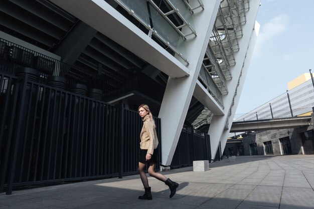 Amazing young blonde lady walking outdoors. Looking aside.