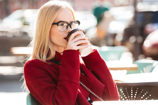 コーヒーを飲みながら電話で話している素晴らしい若い白人女性