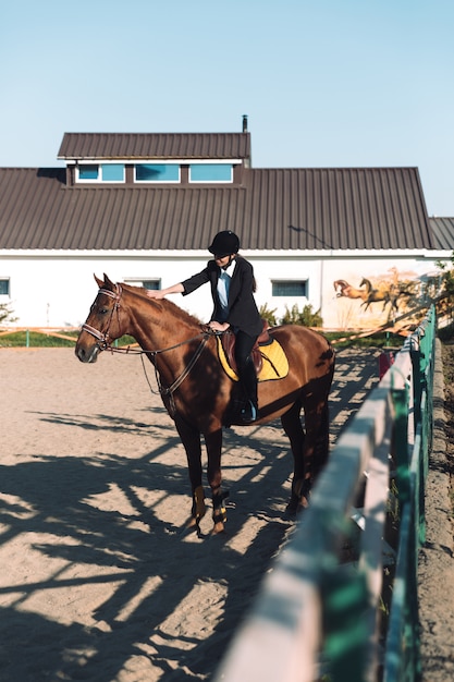 Amazing young cowgirl sitting on horse outdoors