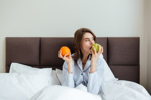 Amazing young lady eating orange and apple