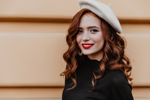 Amazing young lady in french beret enjoying good day. Romantic woman in brown hat standing outdoor.