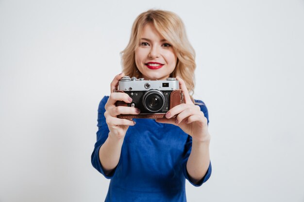 Amazing young lady holding camera over white wall