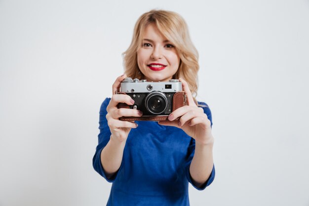 Удивительная молодая леди с фотоаппаратом на белой стене