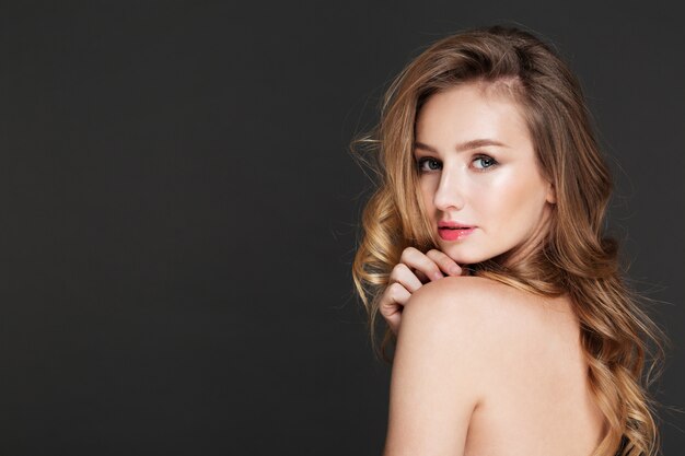 Amazing young woman posing over grey wall