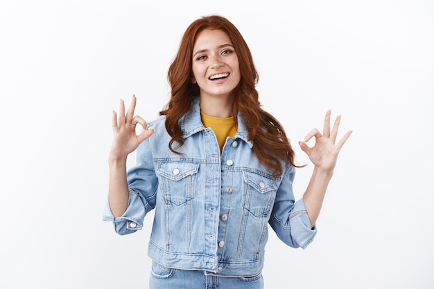 Ambitious confident attractive redhead girl in denim jacket smiling selfassured and relaxed assure everything ok judging good look show okay approval sign and nod in agreemtn grinning goofy