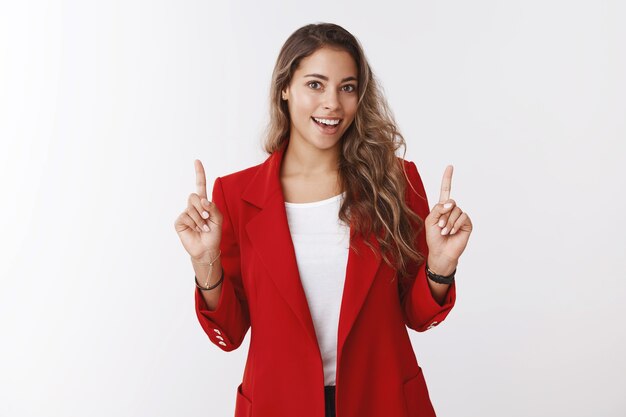 Ambitious good-looking female getting ready important work office presentation raising index fingers up showing upper copy space smiling broadly feeling lucky assured successful result interview