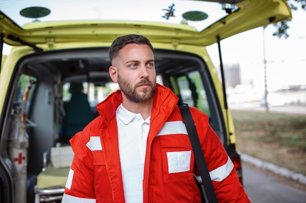 Ambulance staff member emerges from the back of an ambulance with his emergency backpack and vital signs monitor