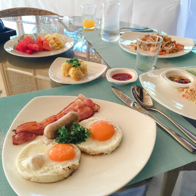 American breakfast. delicious breakfast for one. Woman hands cutting knife egg in a frying pan. View from above. Fried eggs. Top view.