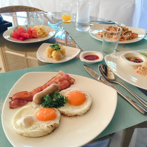 American breakfast. delicious breakfast for one. Woman hands cutting knife egg in a frying pan. View from above. Fried eggs. Top view.