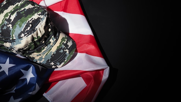 Американский флаг и военная шляпа или сумка. угол обзора сверху. солдатская шляпа или шлем с национальным американским флагом на черном фоне. представьте военную концепцию камуфляжным объектом и национальным флагом сша.