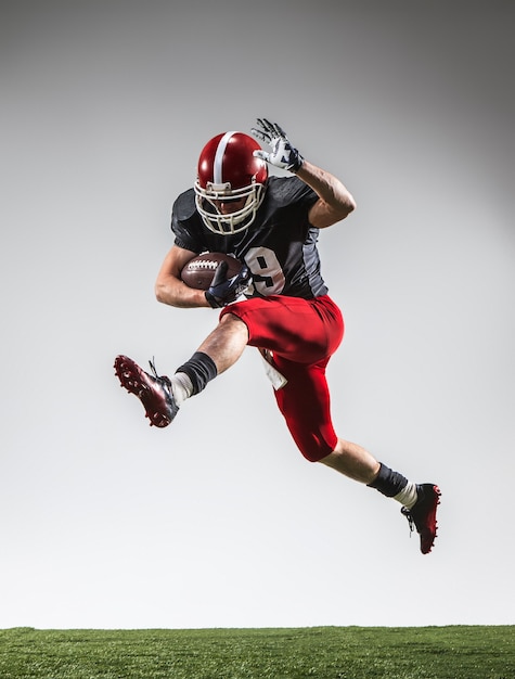 The american football player in action on green grass and gray background.