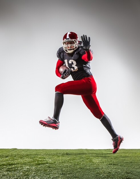 The american football player in action on green grass and gray background.