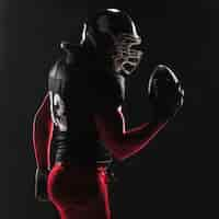 Free photo american football player posing with ball on black background