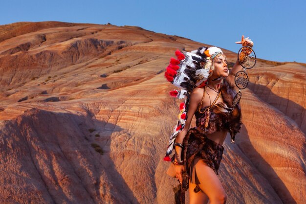 Девушка американских индейцев в национальном костюме в головном уборе из перьев птиц