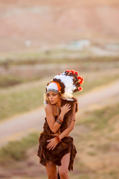 Free photo american indian girl in native costume headdress made of feathers of birds