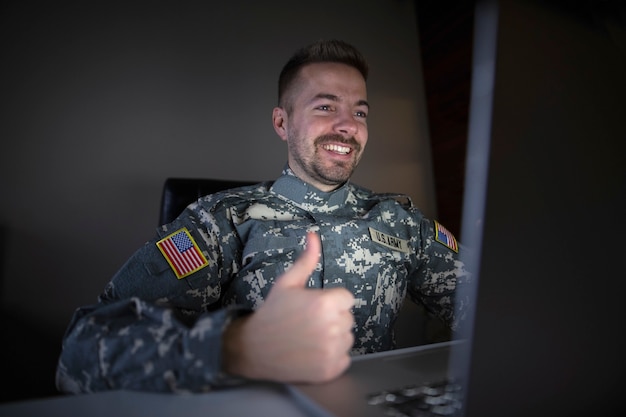 American soldier in military uniform holding thumbs up in front of the computer