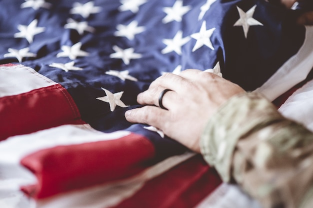 American soldier mourning and praying with the American flag in front of him