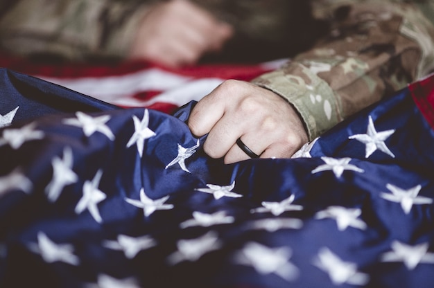 American soldier mourning and praying with the American flag in front of him