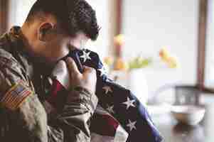 Foto gratuita soldato americano in lutto e in preghiera con la bandiera americana in mano