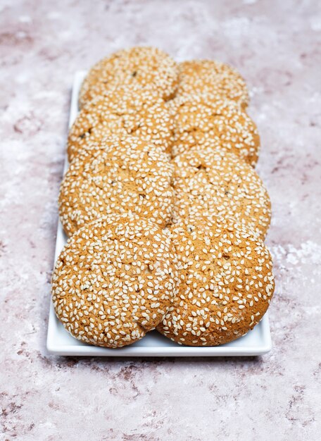 American style sesame seed cookies on light concrete background.