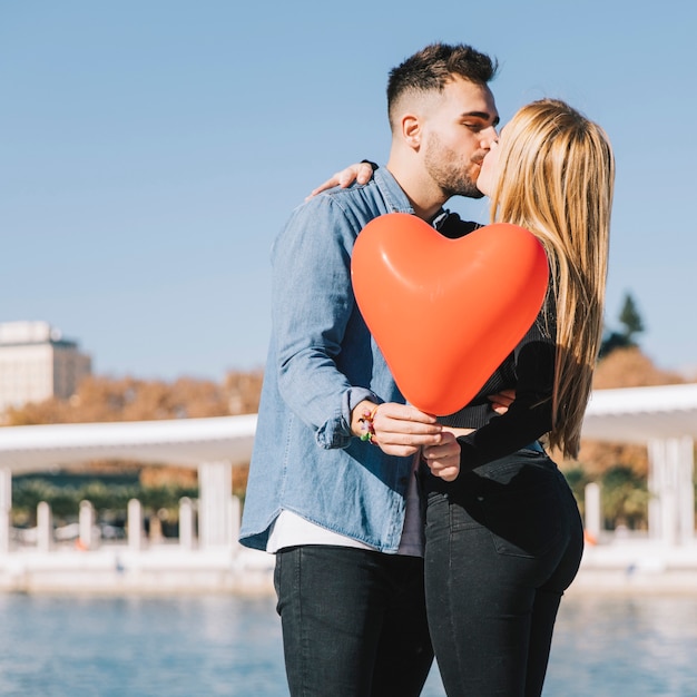 Amorous couple kissing and posing with balloon