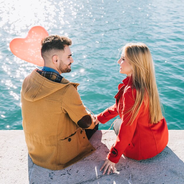 Amorous couple sitting on seafront