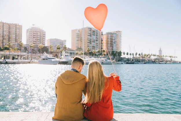 Amorous couple with balloon on romantic embankment