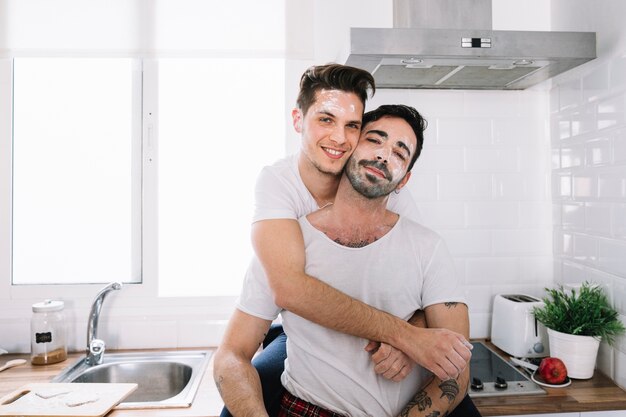 Amorous gay couple posing in kitchen
