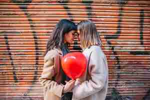 Free photo amorous young girlfriends posing with balloon