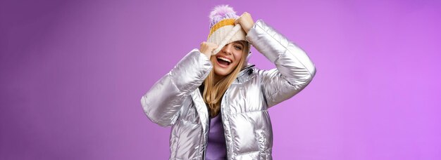 Free photo amused carefree happy smiling playful attractive woman having fun laughing joyfully pulling hat face