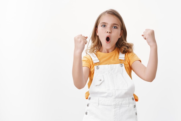 Divertito allegro giovane ragazza bionda, celebrando la vittoria, sentendosi eccitato come vincitore, pompa pugno trionfante, dire sì evviva