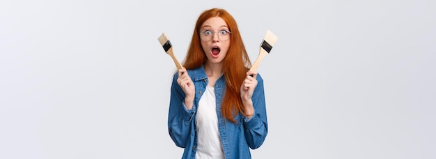 Free photo amused and excited wondered redhead woman creating new art painting look stunned and thrilled say wo