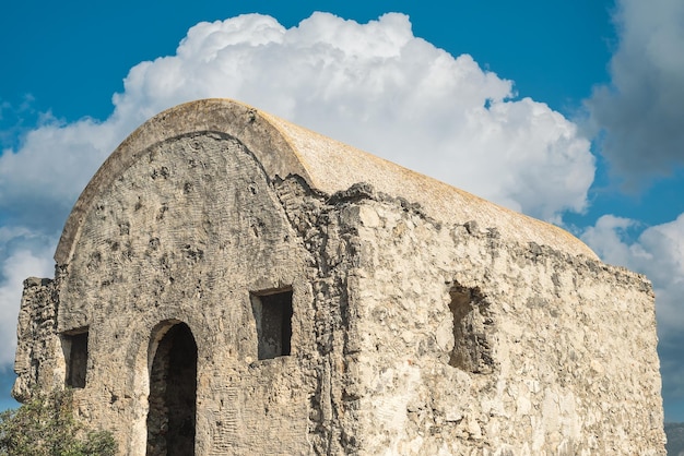 무료 사진 구름과 푸른 하늘을 배경으로 한 버려진 그리스 예배당은 터키 페티예 근처의 버려진 유령 마을에 있는 산에 위치하고 있습니다. 18세기 고대 그리스 도시 karmilissos 사이트