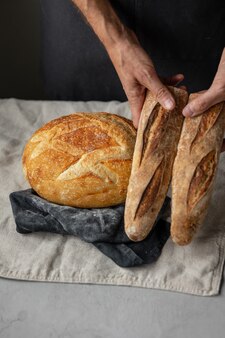 大人のヨーロッパの男性のパン屋は彼の手で丸い焼きたてのパンを持っていますパン屋の男性は Premium写真