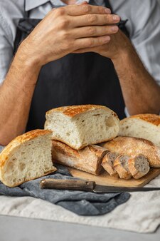 大人のヨーロッパの男性のパン屋は彼の手で丸い焼きたてのパンを持っていますパン屋の男性は