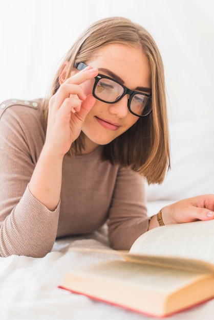 Бесплатное фото Привлекательная молодая женщина в очках чтения книг