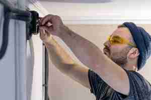 Бесплатное фото Электрик монтирует электрические розетки на белой стене в помещении