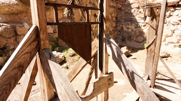 나무 판자와 쇠칼로 만든 오래된 단두대. 고대 고문 도구. 돌담을 배경으로 한 고대 성에서의 사진