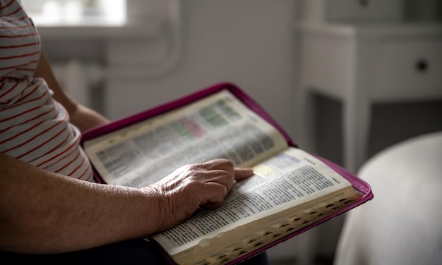 Бесплатное фото Старуха читает библию руками крупным планом