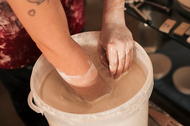 手で塗料を混合する女性の陶工の手の上から見た図