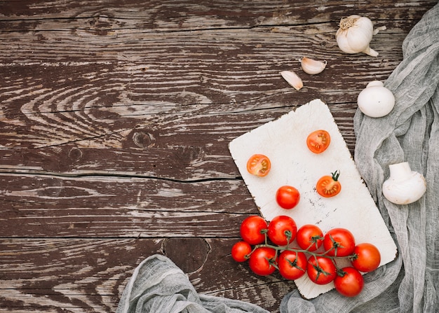 무료 사진 빨간 체리 토마토의 오버 헤드보기; 다진 마늘과 버섯 나무 테이블에
