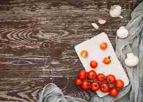 Бесплатное фото Вид сверху на красные помидоры черри; зубчики чеснока и гриб на деревянном столе