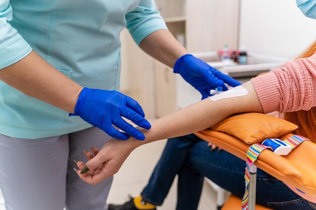 주사기로 알아볼 수 없는 의사가 검사를 위해 혈액을 채취하고 있습니다. 팔의 일부에 선택적 초점입니다. 클리닉 배경입니다.