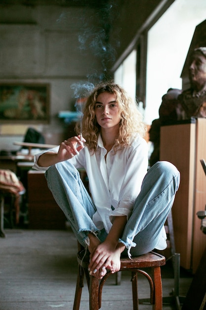 담배를 피우면서 실내에서 포즈를 취하는 아름다운 여성의 아날로그 초상화